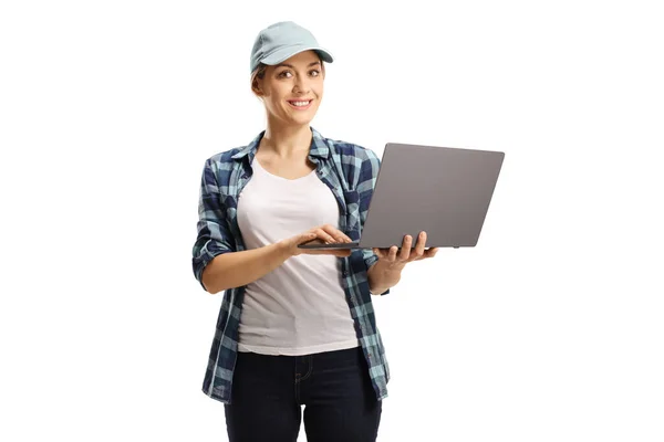年轻的女人 戴着帽子 穿着格子衬衫 手里拿着笔记本电脑 看着被白色背景隔离的相机 — 图库照片