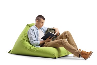 Yeşil fasülye koltukta oturan ve beyaz arka planda izole edilmiş bir kitap okuyan adam.