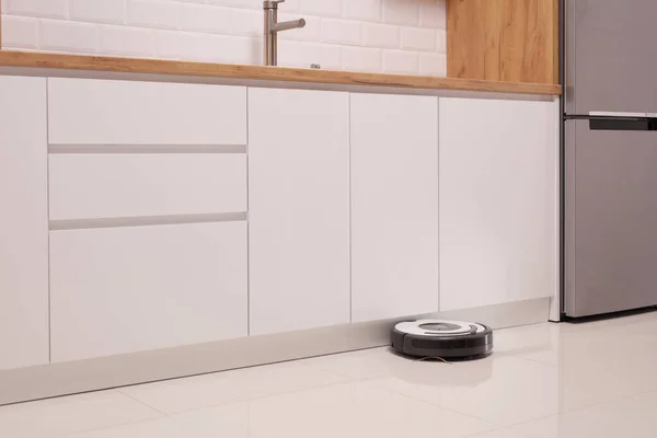 Robot vacuum cleaner on a tiled kitchen floor