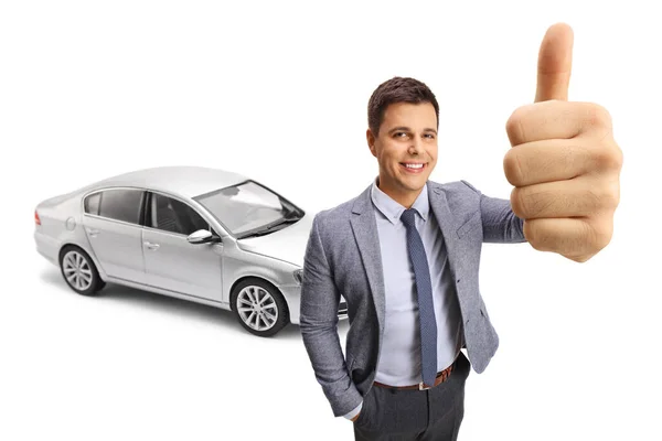 白い背景に孤立した新しい銀の車の前に親指を示す幸せな若い男 — ストック写真