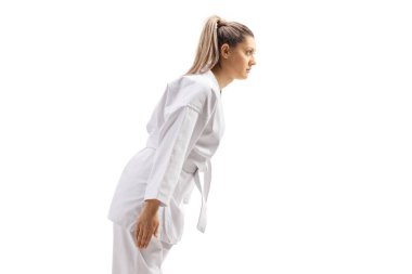 Karate kimonolu genç bir kadın beyaz arka planda izole bir şekilde selam veriyor.