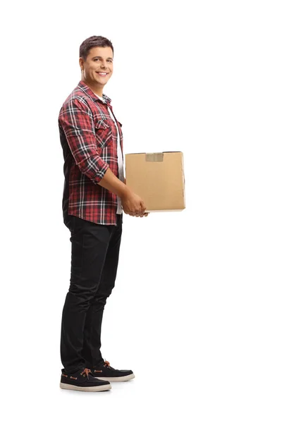 段ボールの箱を持っている若い男の完全な長さのショットと笑顔白い背景に隔離された — ストック写真