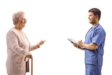 Yaşlı bir kadın, beyaz arka planda, mavi üniformalı genç bir doktorla konuşuyor.
