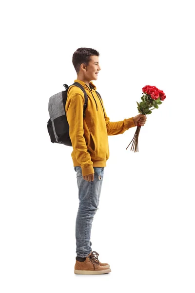 フル長さプロフィールショットの男十代の学生持っていますA束の赤いバラ孤立した上の白い背景 — ストック写真