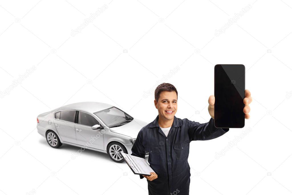 Auto mechanic holding a mobile phone in front of a silver car isolated on white background