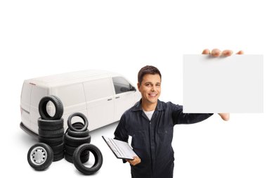 Beyaz bir minibüsün önünde oto tamircisi ve beyaz arka planda izole edilmiş boş bir kart tutan lastikler.