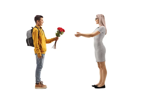 一个十几岁的男孩送给一个有着白种人背景的女子一束红玫瑰的全景照片 — 图库照片