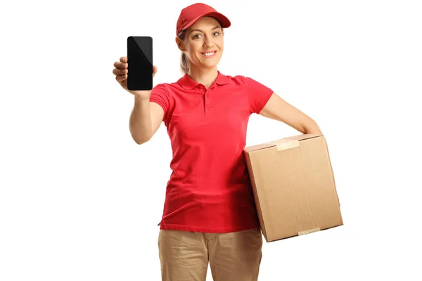 赤いTシャツを着た女性配達員が箱を持っていて 白い背景に孤立した携帯電話を示しています — ストック写真