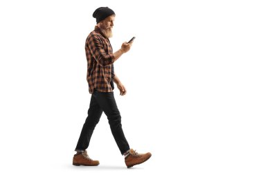 Kareli gömlekli, kot pantolonlu ve beyaz arka planda izole edilmiş bir cep telefonu kullanan bir gencin tam boy profil fotoğrafı.