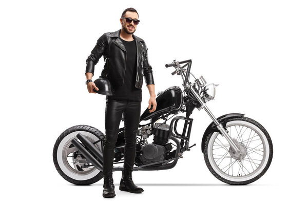 Full length portrait of a biker in leather jacket and pants with a chopper motorbike isolated on white background