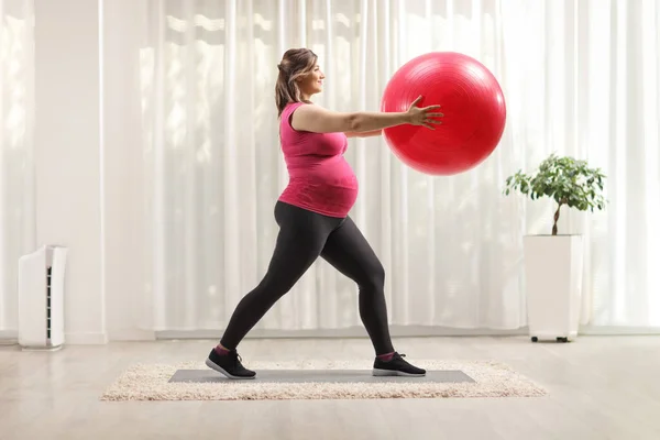 怀孕妇女在家里带着红色健身球进行运动 — 图库照片