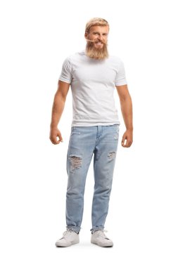 Bıyıklı, sakallı, beyaz tişörtlü ve kot pantolonlu, beyaz arka planda sarışın bir adamın tam boy portresi.