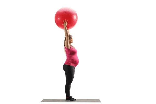 白い背景に隔離されたフィットネスボールを持ち上げる妊娠中の女性のフル長プロファイルショット — ストック写真