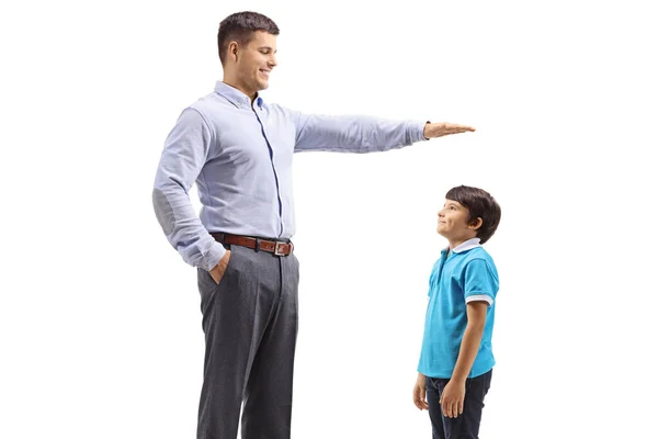 白い背景に孤立した少年の身長を測定する男 — ストック写真