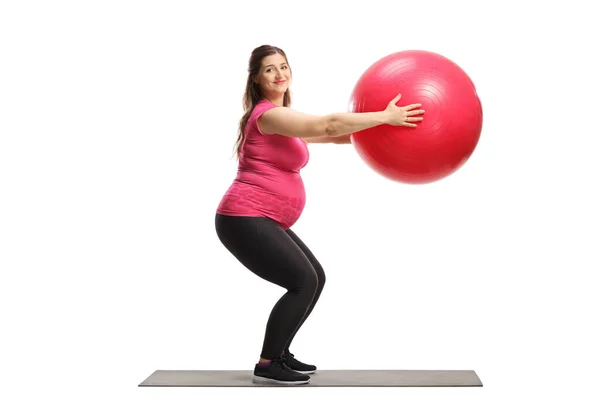 一个孕妇拿着健身球运动 看着白色背景的摄像机的全长镜头 — 图库照片