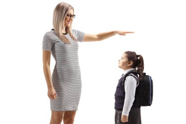 Genç bir kadın el kol hareketi yapıyor ve beyaz arka planda izole edilmiş bir kız öğrencinin boyunu gösteriyor.