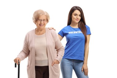 Bastonlu yaşlı bir bayan ve beyaz arka planda izole edilmiş genç bir kadın gönüllü.