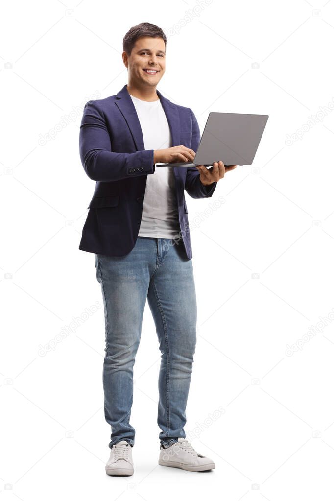 Full length portrait of a young man holding an open laptop computer and smiling at camera isolated on white background