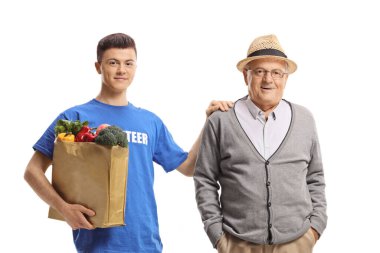Bakkal çantası taşıyan genç gönüllü ve yaşlı bir adam, beyaz arka planda izole edilmiş yaşlı vatandaşların konseptine yardım ediyor.