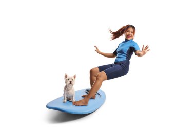 Dalış kıyafetli bir kadın beyaz arka planda izole edilmiş bir köpekle sörf tahtası sürüyor.