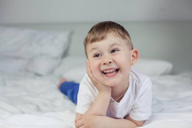 Sevimli küçük çocuk yatağa yatıyor. 4 yaşında bir çocuk yatağa çalış. Mutlu bir çocuk. Rekreasyon. Uyku. Sabah. Rahat.