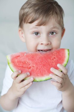 Küçük sevimli çocuk 4 yaşında bir karpuz yiyor. Yaz. Isı. Karpuz. Bir karpuz ile mutlu bir çocuk portresi. Parlak tonlar. Rahat.