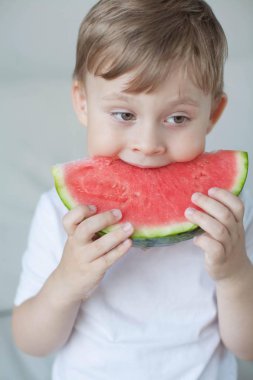 Küçük sevimli çocuk 4 yaşında bir karpuz yiyor. Yaz. Isı. Karpuz. Bir karpuz ile mutlu bir çocuk portresi. Parlak tonlar. Rahat.