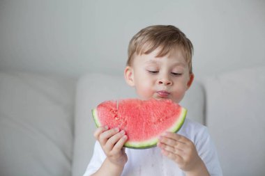 Küçük sevimli çocuk 4 yaşında bir karpuz yiyor. Yaz. Isı. Karpuz. Bir karpuz ile mutlu bir çocuk portresi. Parlak tonlar. Rahat.