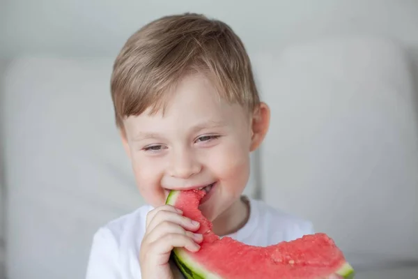 Ein kleiner netter Junge von 4 Jahren isst eine Wassermelone. Sommer. Hitze. Wassermelone. Porträt eines glücklichen Jungen mit einer Wassermelone. helle Farbtöne. — Stockfoto