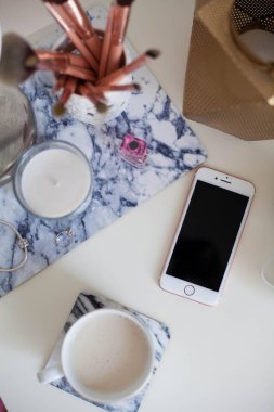 Bir fincan kapuçino, kozmetik, çiçekler, kostüm takı beyaz bir tablo. Tuvalet masası. Rahat. Bahar