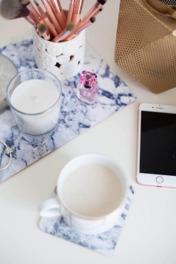 Bir fincan kapuçino, kozmetik, çiçekler, kostüm takı beyaz bir tablo. Tuvalet masası. Rahat. Bahar