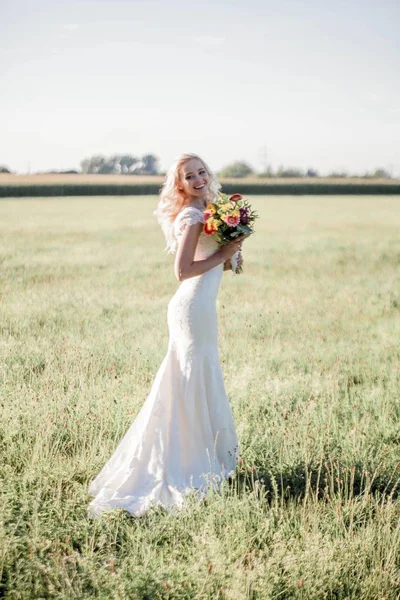 太陽の下で美しい花嫁の肖像画 ウェディング ドレスの若い幸せな女は フィールドで歩いています 居心地の良い — ストック写真