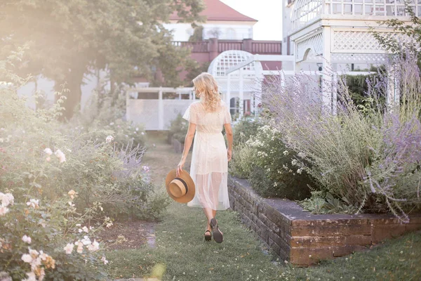 日光の女の子の肖像画 若いブロンドは カラフルな庭園で歩いています 若い女性は 花と麦わら帽子に保持しています ラベンダー — ストック写真