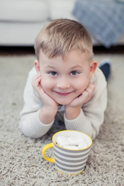 Bir rahat sonbahar portre tatlı bir çocuk. 4 yaşında küçük bir çocuk bir halı üzerinde oturur ve kakao içiyor. Sonbahar.