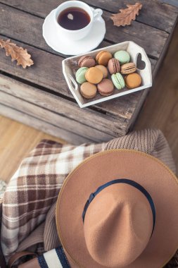 Bir fincan sıcak çay, kurabiye, örme kazak, şapka, ahşap bir masa üzerinde bir halı. Sonbahar. Rahat.