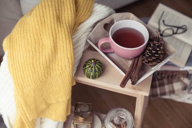 Örgü, kazak, bir fincan sıcak çay, Sonbahar dekorasyonu, bir kitap, bir kabak ahşap sandalye üzerinde sıcak. Rahat, Sonbahar dekorasyonu. Sonbahar iç, kanepe. Sonbahar. Kış.