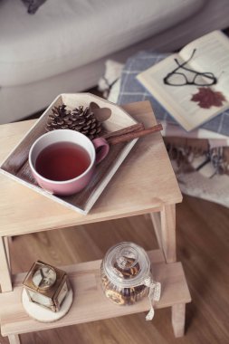 İskoç şalılar. Bir fincan çay. Sonbahar rahat iç. Bir tahta sandalyede bir yığın sıcak battaniye var. Mumlar, yaprakları, koniler, sepet, tarçın. Kitap ve gözlük. Sonbahar.