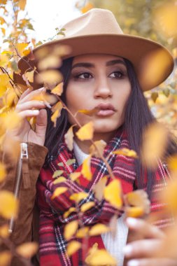 Güzel, Genç bir Türk kadın sarı ağaçlarda portresi. Sıcak sonbahar. Mutlu esmer sonbahar parkta yürüyor. Şapkalı kız. Moda. Sarı yapraklar.