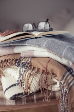 İskoç şalılar. Sonbahar rahat iç. Bir tahta sandalyede bir yığın sıcak battaniye var. Kitap ve gözlük. Sonbahar. Kış.