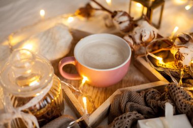 Bir fincan sıcak cappuccino bir ahşap tepsi yatağım. Rahat dekor. Kahvaltı. Kupa, ekose, pamuk, mum. Hediye kutusu ve örme eldivenler. Noel ışıkları. Tatil.