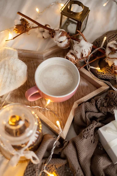 Bir fincan sıcak cappuccino bir ahşap tepsi yatağım. Rahat dekor. Kahvaltı. Kupa, ekose, pamuk, mum. Hediye kutusu ve örme eldivenler. Noel ışıkları. Tatil.