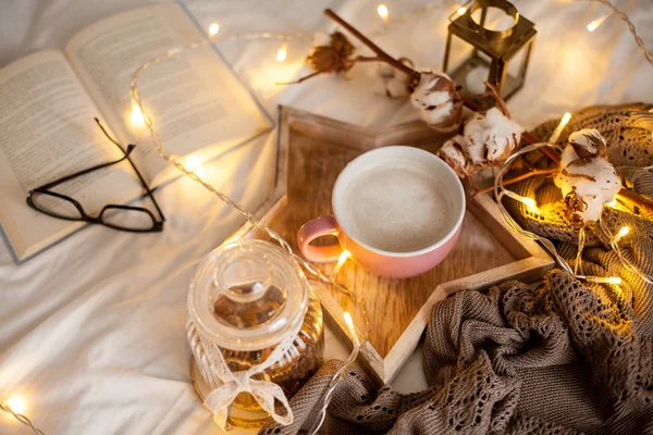 Bir fincan sıcak cappuccino bir ahşap tepsi yatağım. Rahat dekor. Kahvaltı. Kupa, ekose, pamuk, mum. Kitap. Noel ışıkları. Tatil.