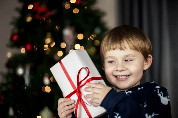 Menino Bonito Sentado Perto Árvore Natal Segurando Uma Caixa Com — Fotografia de Stock