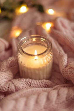 Rahat dekor. Bir fincan kapuçino. Bir cam kavanozun içinde mum, pembe örgü battaniye, gül, laptop. Rahat. Sonbahar.