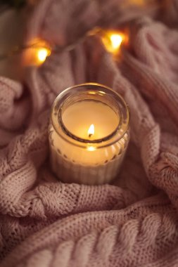 Rahat dekor. Bir fincan kapuçino. Bir cam kavanozun içinde mum, pembe örgü battaniye, gül, laptop. Rahat. Sonbahar.