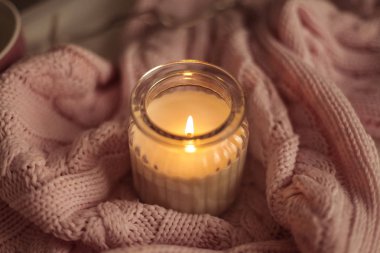 Rahat dekor. Bir fincan kapuçino. Bir cam kavanozun içinde mum, pembe örgü battaniye, gül, laptop. Rahat. Sonbahar.