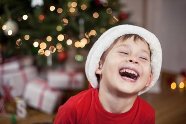 Noel ağacı yakınındaki bir Noel Baba şapkalı bir mutlu 4 yaşındaki çocuk portresi. Noel. Tatil. Yeni yıl. Mutluluk. Çocuk. Rahat.