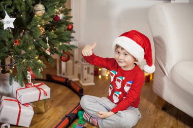 Noel ağacı yakınındaki bir Noel Baba şapkalı bir mutlu 4 yaşındaki çocuk portresi. Noel. Tatil. Yeni yıl. Mutluluk. Çocuk. Rahat.