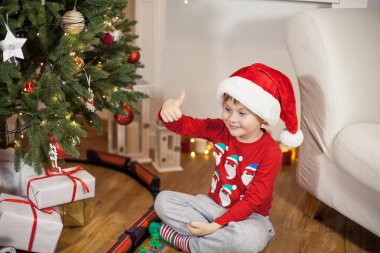 Noel ağacı yakınındaki bir Noel Baba şapkalı bir mutlu 4 yaşındaki çocuk portresi. Noel. Tatil. Yeni yıl. Mutluluk. Çocuk. Rahat.