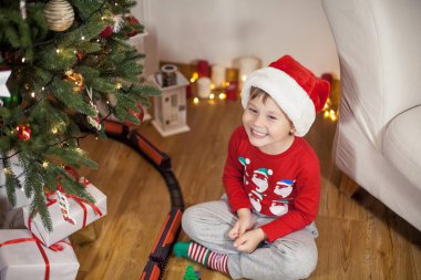 Noel ağacı yakınındaki bir Noel Baba şapkalı bir mutlu 4 yaşındaki çocuk portresi. Noel. Tatil. Yeni yıl. Mutluluk. Çocuk. Rahat.